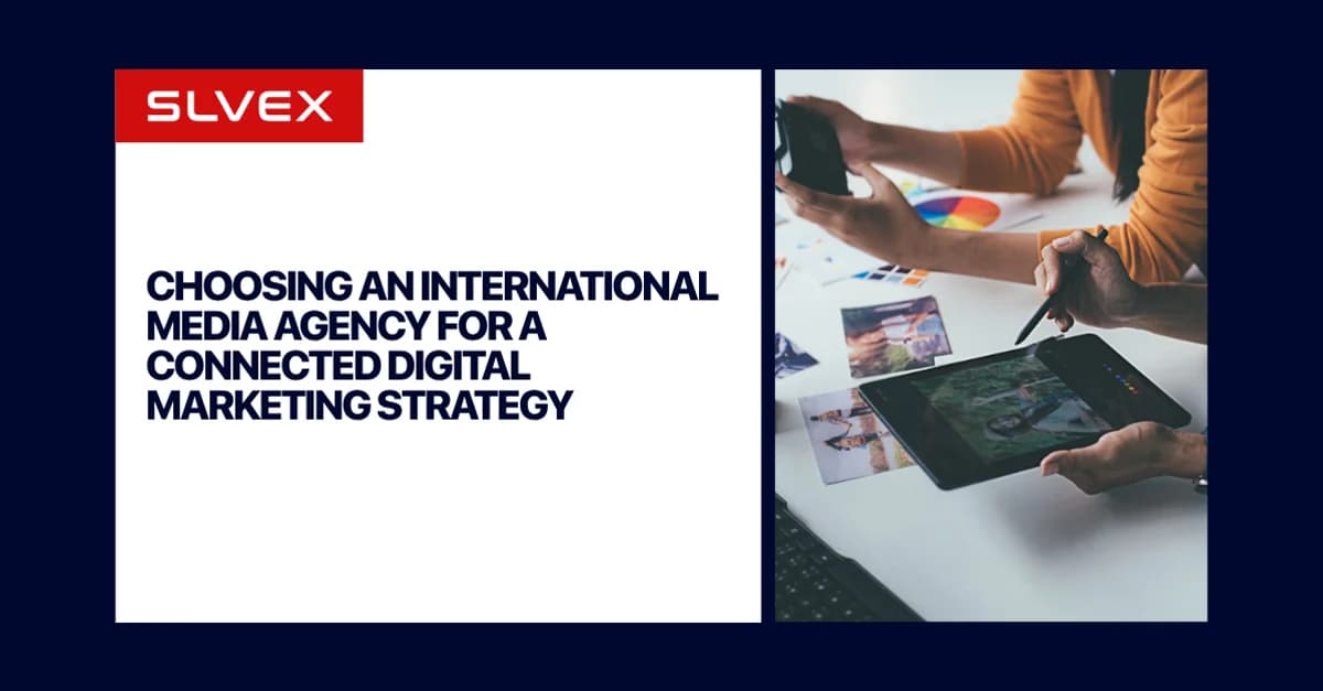 Tarjeta de título de SLVEX con el texto Choosing an International Media Agency for a Connected Digital Marketing Strategy, junto a un equipo creativo revisando fotos en una tableta.
