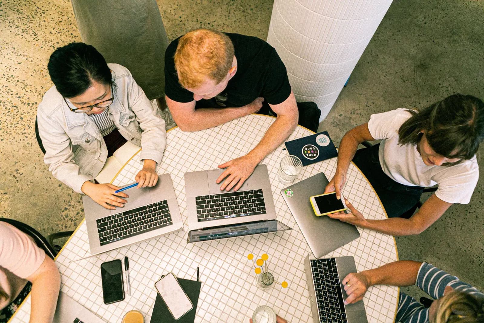 Overhead view of a marketing team working on laptops around a shared table.