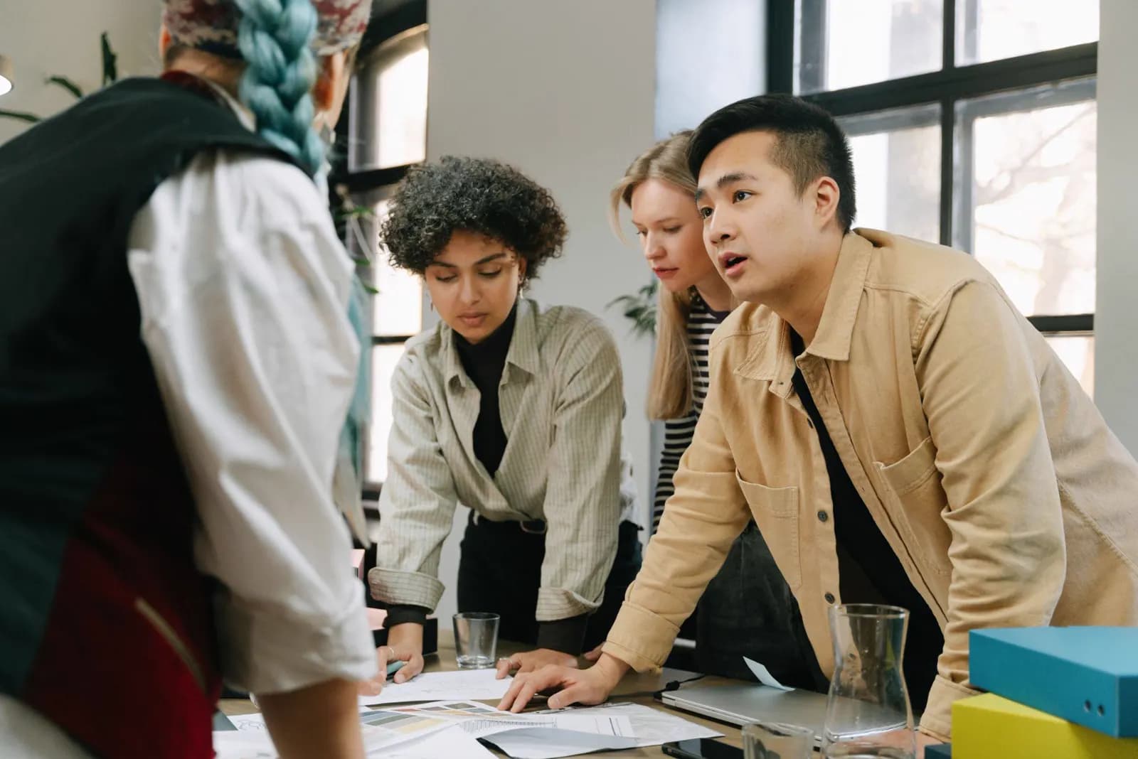 Marketing team leaning over a table to review campaign documents together.